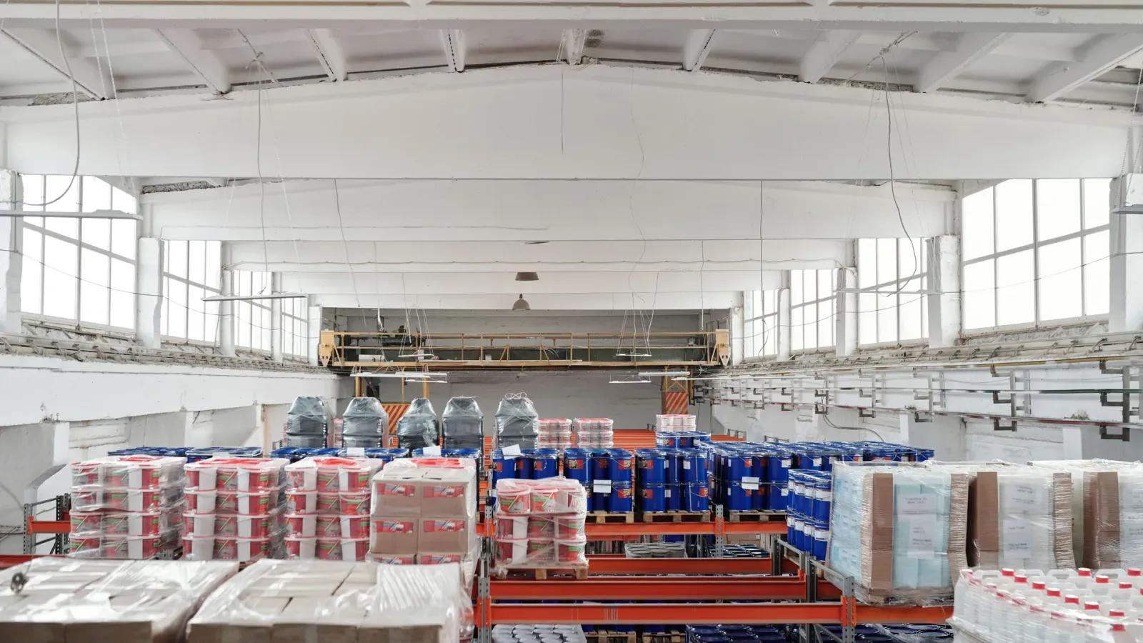 Large wholesale warehouse with varied goods organized in palletized stock zones