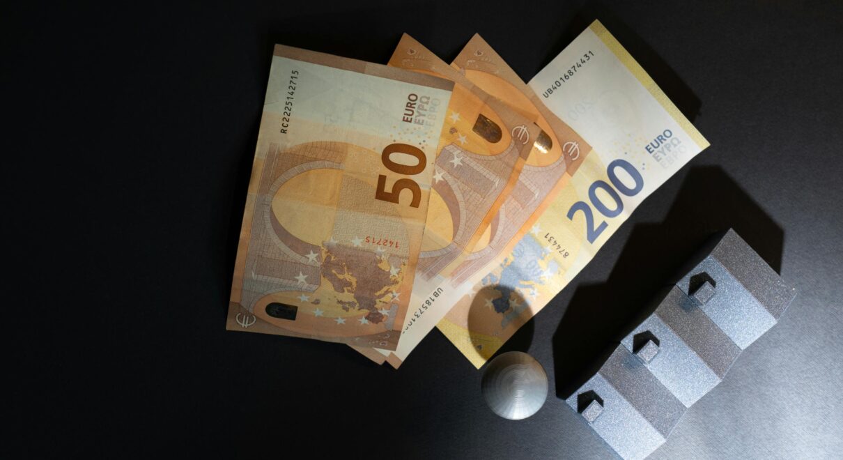 Close-up of Euro banknotes and model houses on dark background symbolizing real estate investment.