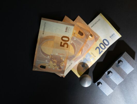 Close-up of Euro banknotes and model houses on dark background symbolizing real estate investment.