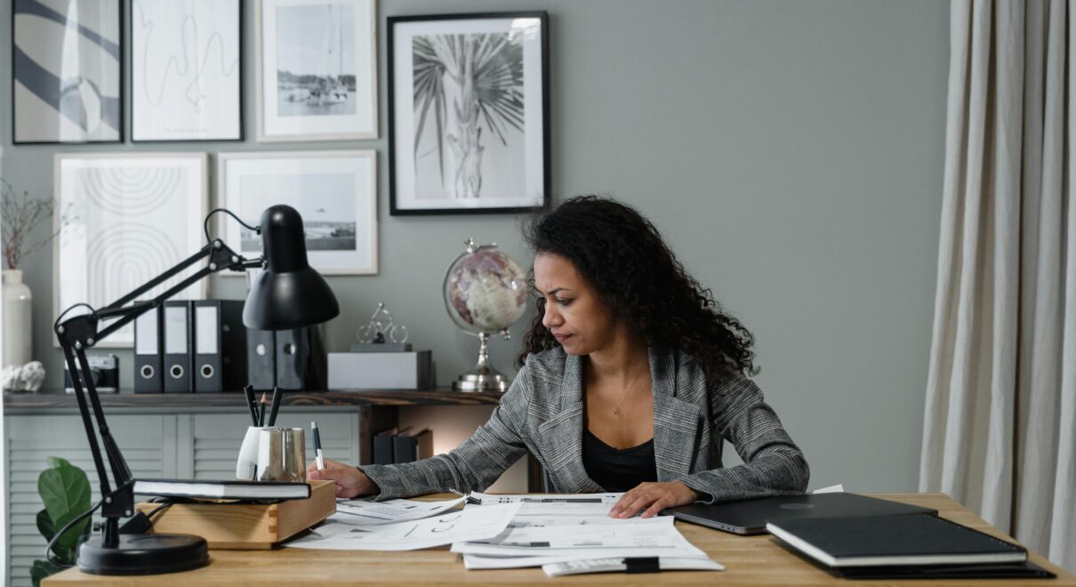 Businesswoman evaluates documents at a modern desk in a stylish office setting.