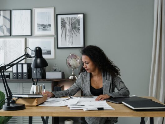 Businesswoman evaluates documents at a modern desk in a stylish office setting.