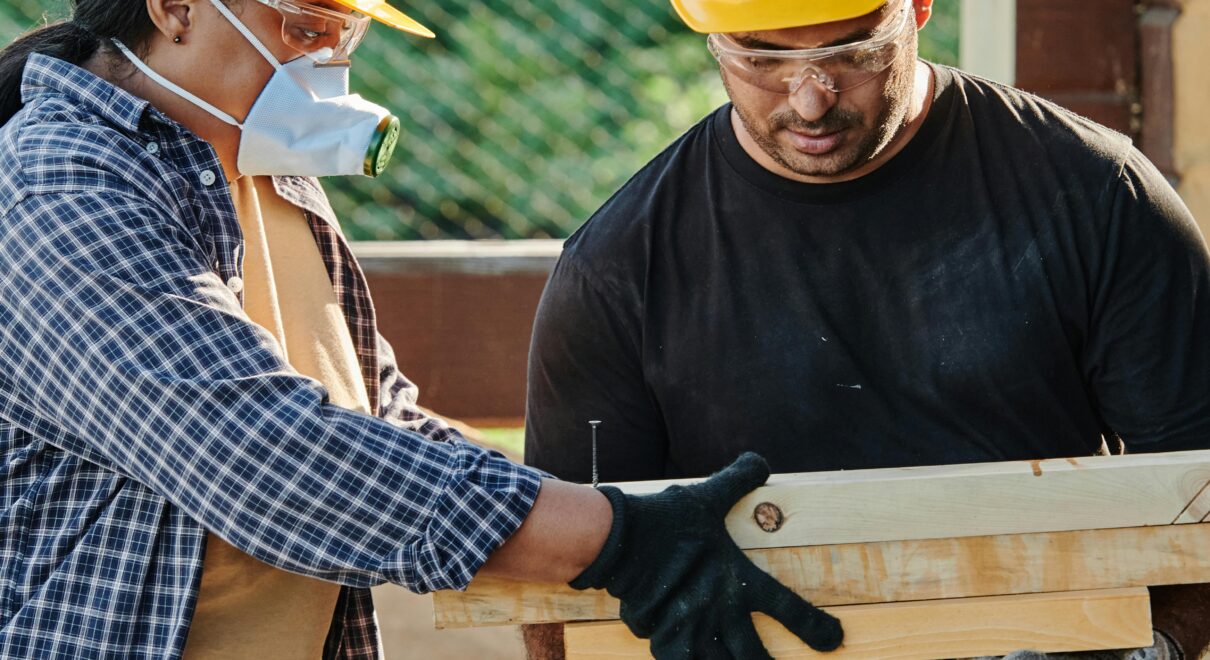 Two construction workers in hard hats collaborating at an outdoor site.