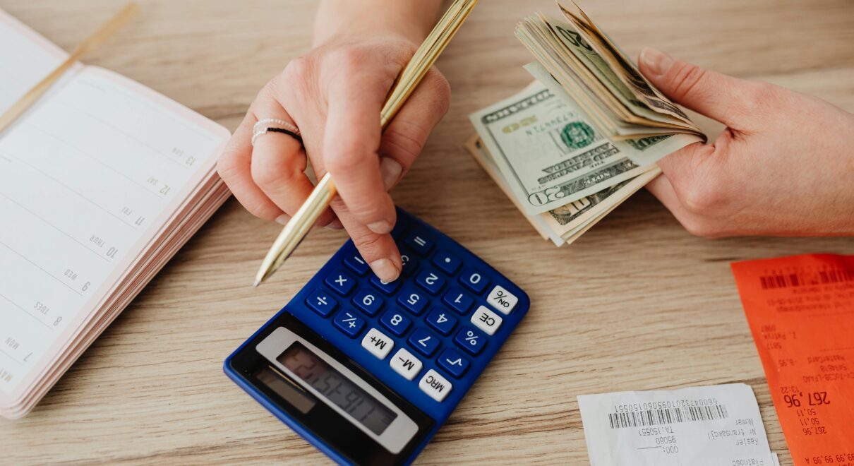 Hands handling cash and calculator for budget planning. Modern financial scene.
