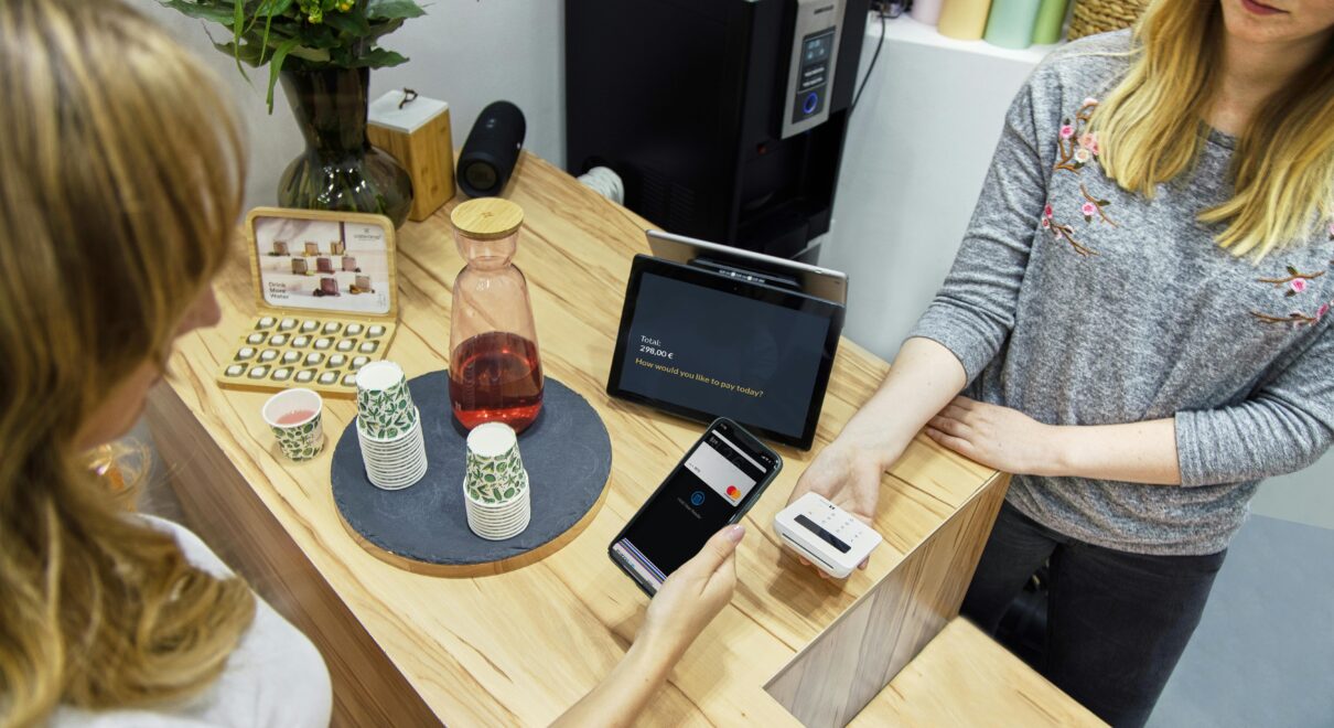 A woman makes a contactless payment at a stylish Berlin café, emphasizing technology and modern retail.